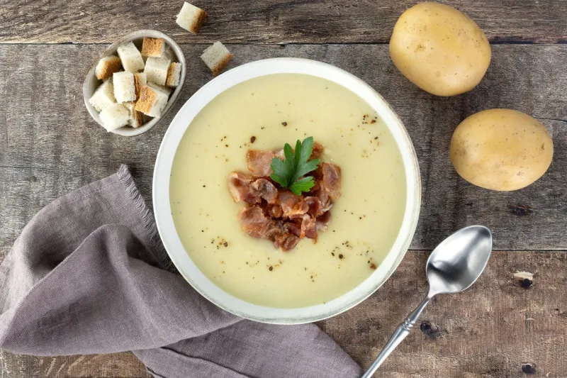 creamy potato soup with bacon, croutons, ingredients on a wooden background top view french vichyssoise soup