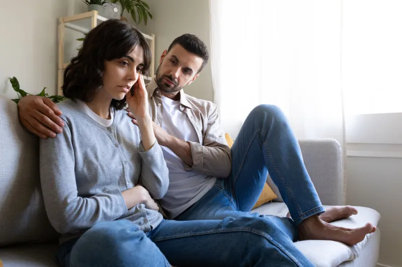 young couple having relationship problems sitting on sofa at home