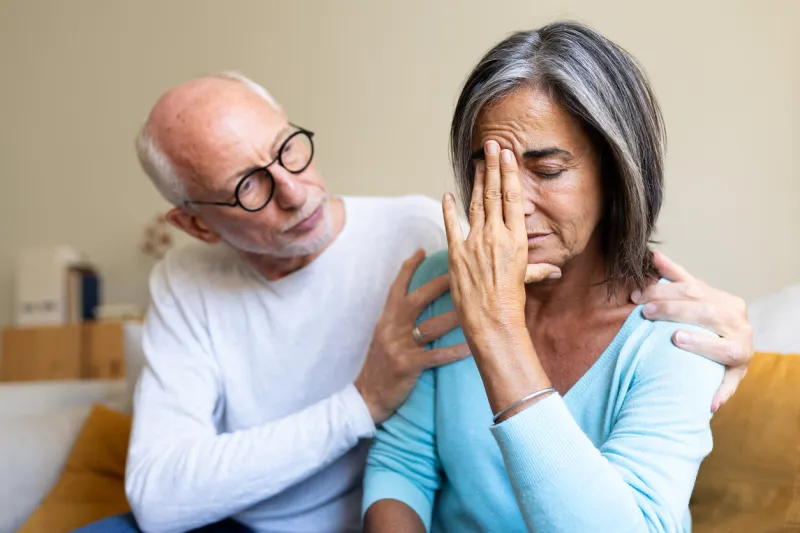 loving senior man comforts his sad senior wife at home