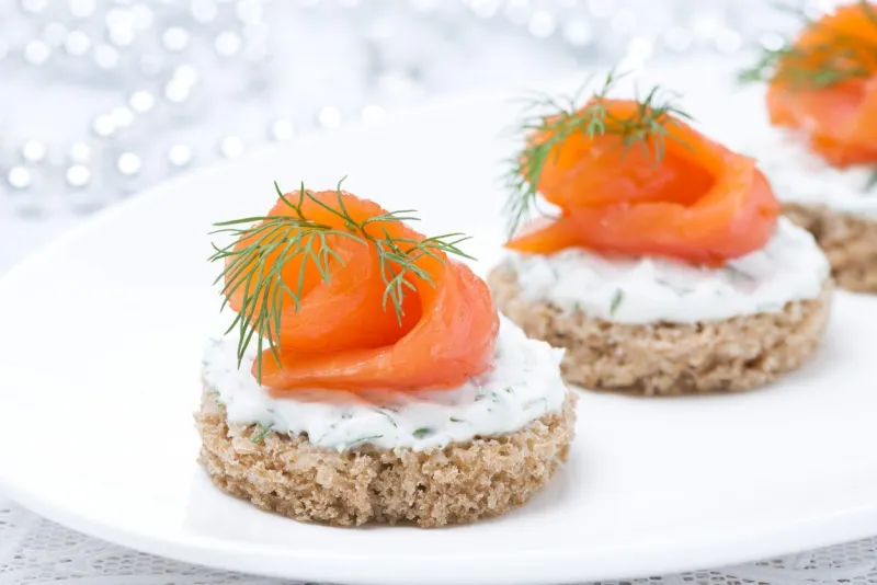 canape with rye bread, cream cheese, salmon and greens for the holiday, close-up