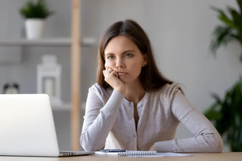 bored young woman sit at home office table look in distance unable to work at laptop, exhausted girl student feel unmotivated unwilling to study, distracted taking break dull monotonous job concept