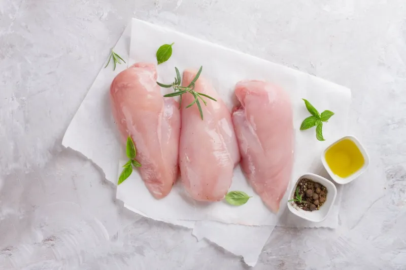 raw chicken breast with rosemary, olive oil and peppercorns, selective focus culinary cooking ingredients