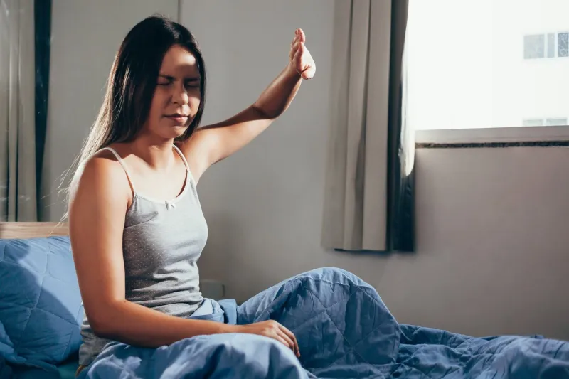 girl upset waking up with the light bothering her lying on a bed in the morning
