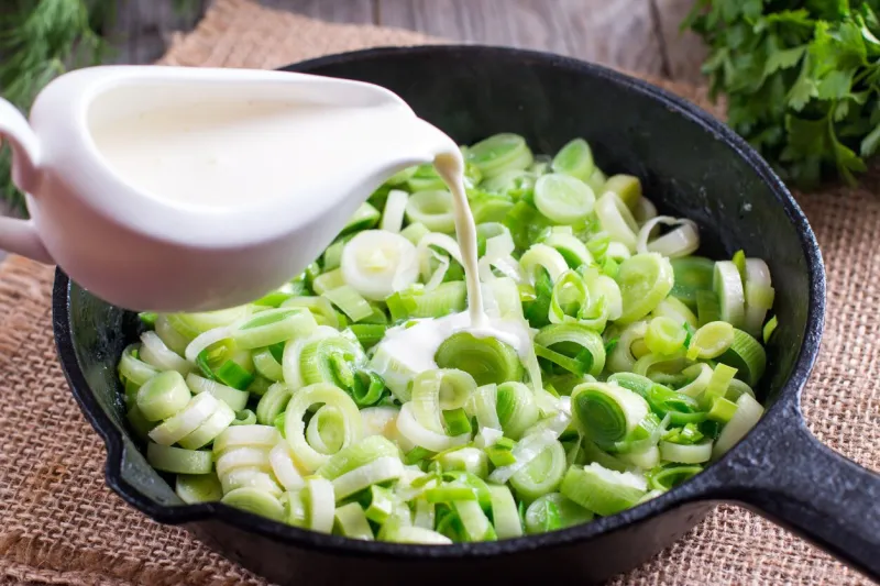 stewing leek slices in a frying pan with cream