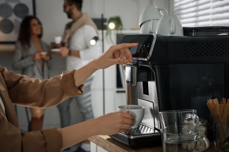 woman preparing fresh aromatic coffee with modern machine in office, closeup