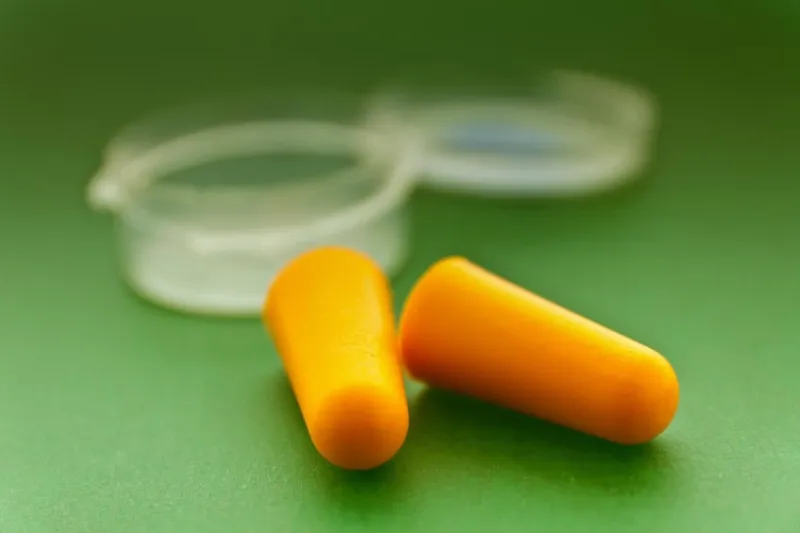 protecteurs d'oreilles orange et étui sur fond vert