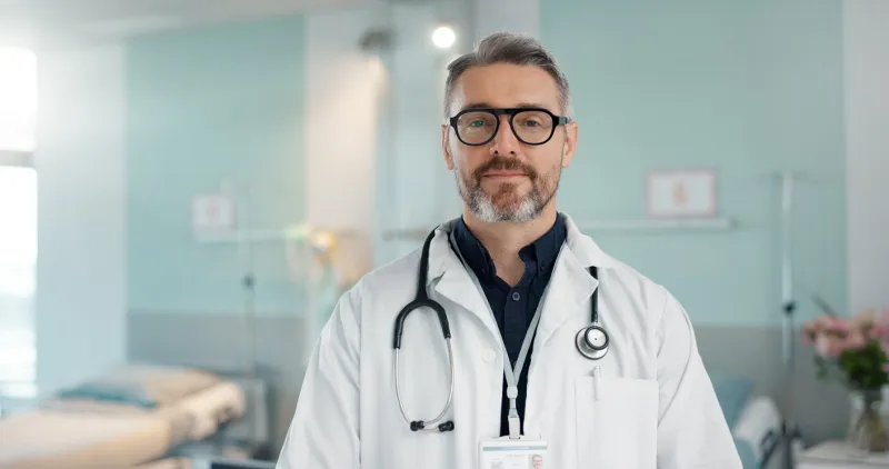 healthcare, doctor and man with arms crossed at hospital with smile for support, service and wellness medicine, professional and expert with glasses and pride for career, surgery, insurance and care