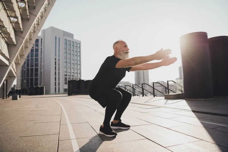 photo of pretty confident retired man black sportswear doing sitting up exercises outside urban city street