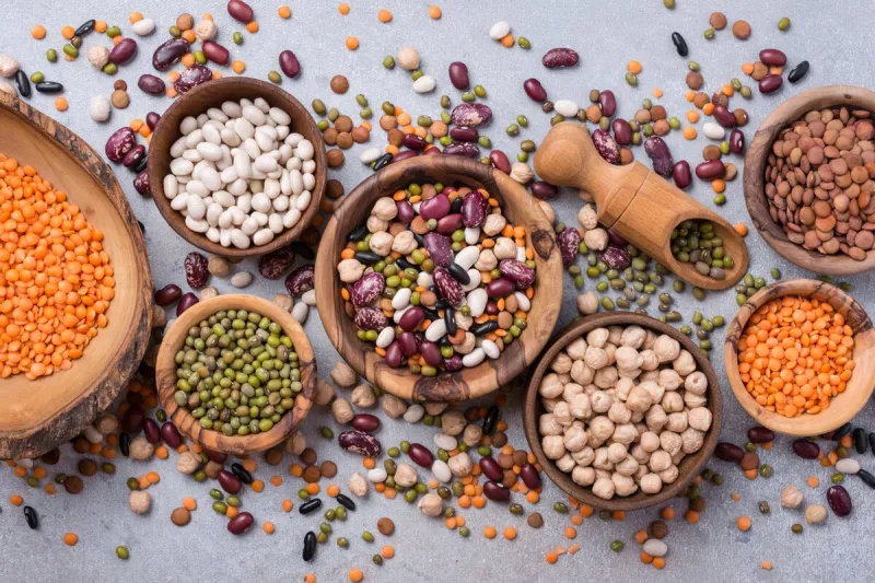 top view of different beans, lentils, mung, chickpeas in wooden bowls for tasty meals on grey concrete background