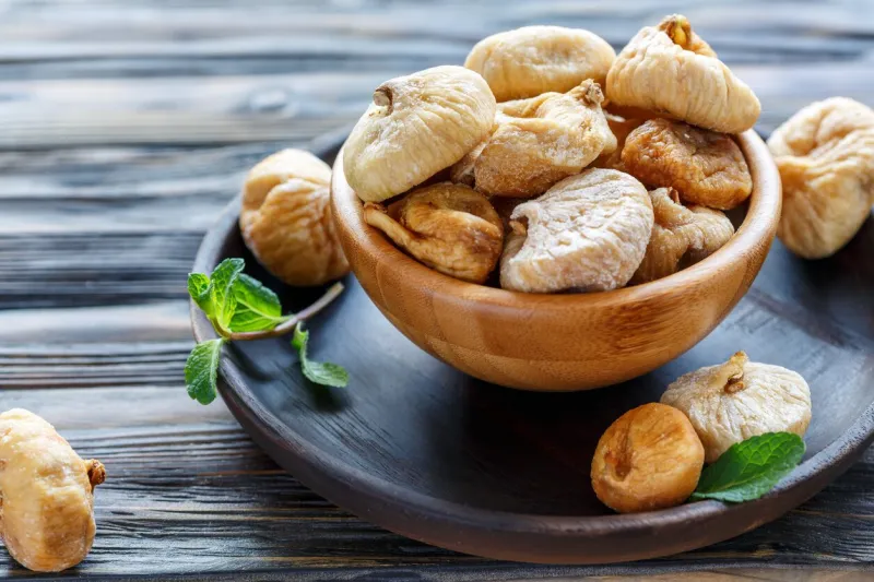 sweet dried figs in a bowl on wooden table, selective focus