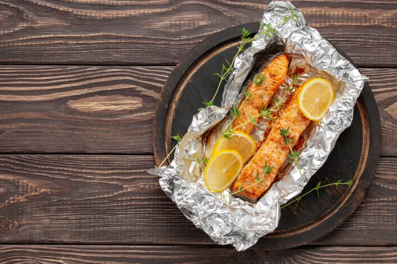 baked salmon infoil with lemon on wooden background mediterranean diet concept copy space