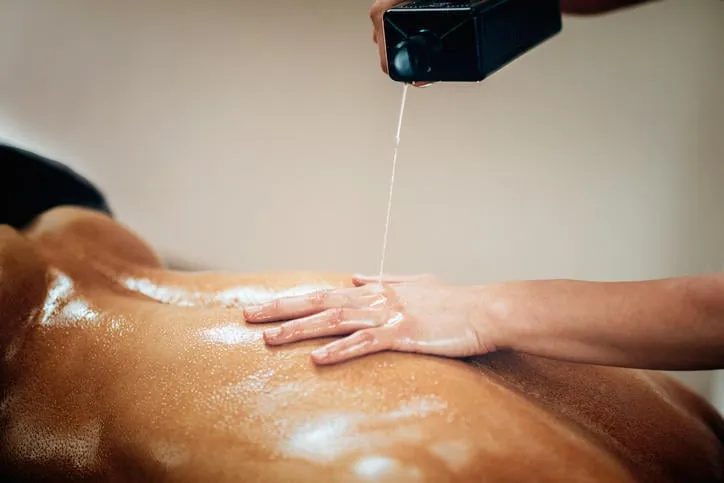 massage sportif kinésithérapeute mettant l'huile de massage