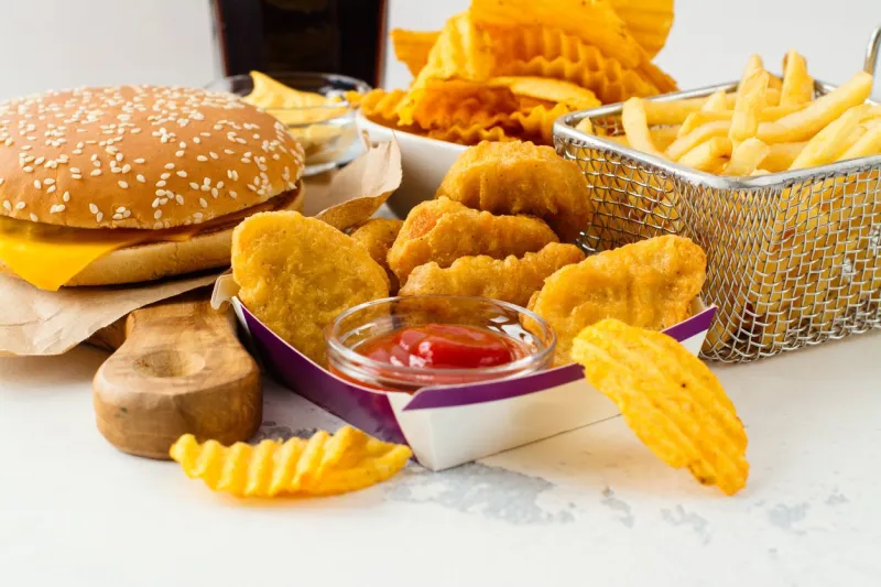 junk food on white table fast carbohydrates not good for health, heart and skin
