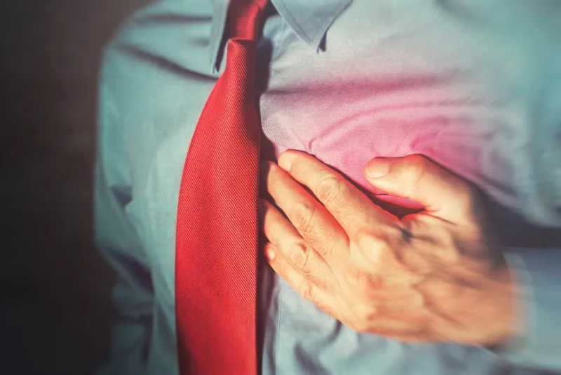 unrecognizable businessman having chest pain and heart attack, hand holding the painful spot