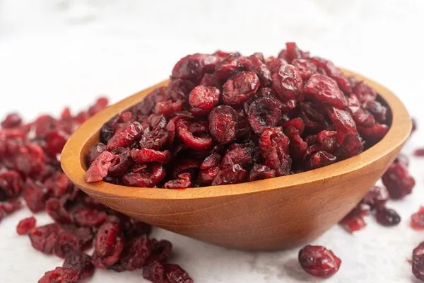 dried organic cranberry in wooden bowl on white table background