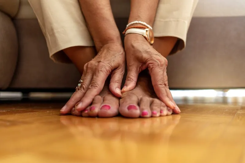 close up of senior woman hands touching legs with varicose veins, sitting on sofa at home woman suffering from ankle pain an older woman massages her feet to relieve the pain caused by arthritis