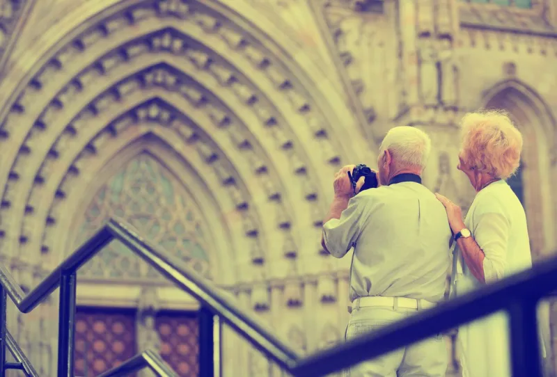 back view of cheerful positive senior couple travellers making photo with camera while sightseeing
