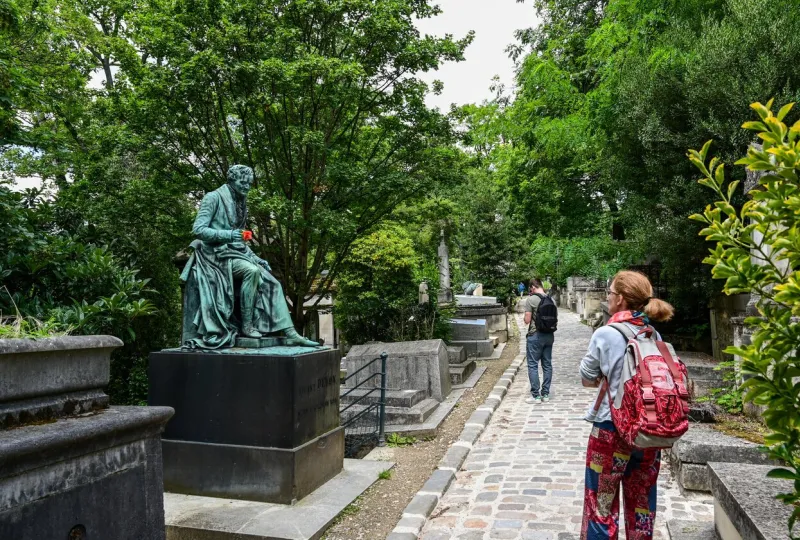 the characteristic and historic cemetery of pere lachaise, shot of one of the cobbled paths with tourists intent on observing the tombs of famous people