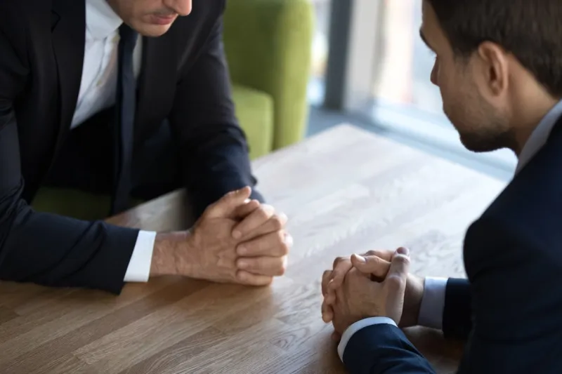 close up two businessmen negotiators with clasped hands, debate dialogue concept, opponents sitting opposite at table, business partners negotiations, confrontation, struggle for leadership, conflict