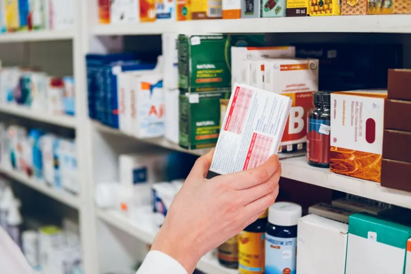 a young female pharmacist arranges medicines on the shelves of the pharmacy and makes an inventory