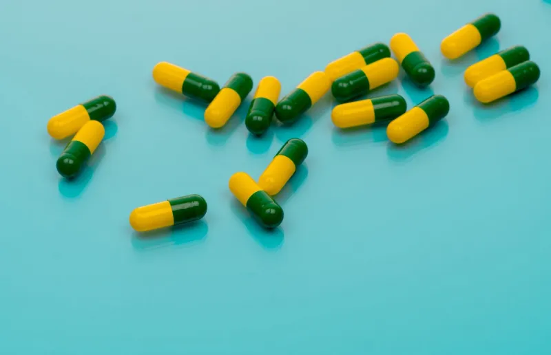 green-yellow capsules spread on blue background tramadol capsule pills for relieve severe cancer pain painkiller medicine opioids drug pharmaceutical product for pain treatment prescription drug