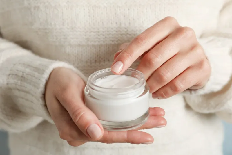 woman holding jar of moisturizing cream, closeup winter cosmetic space for text