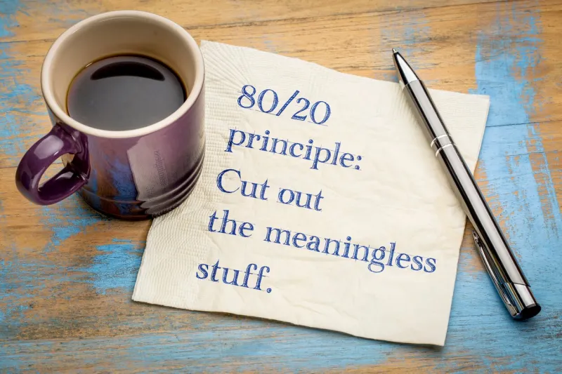 80-20 principle  cut out the meaningless stuff - inspirational handwriitng on a napkin with a cup of coffee
