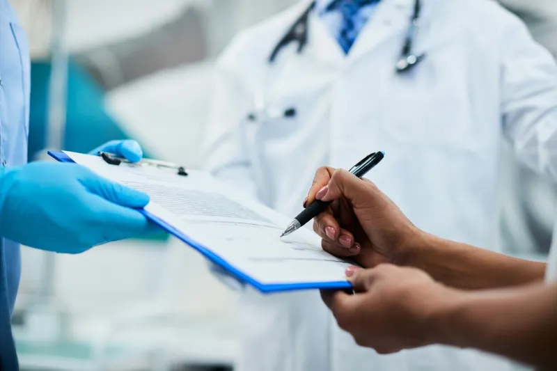 close-up of african american woman signing paperwork during medical appointment at clinic