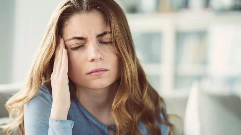 young woman with headache in home interior