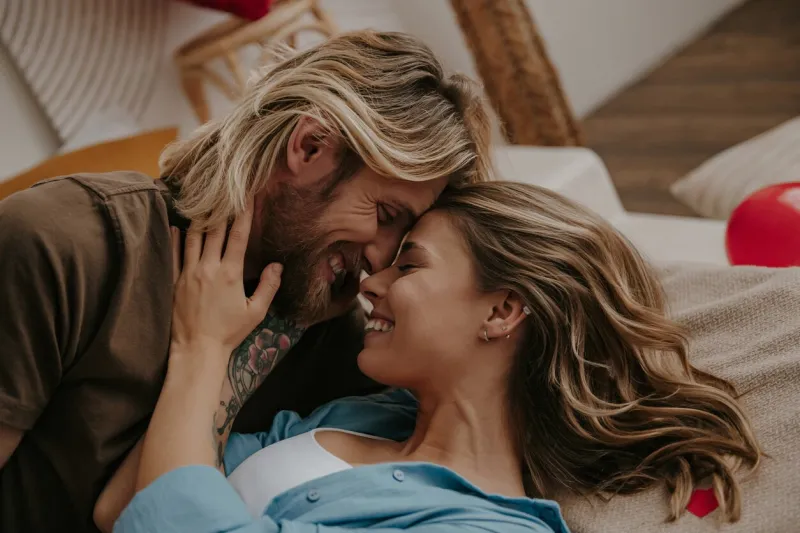 close-up of happy loving couple embracing and smiling while lying down in bed at home