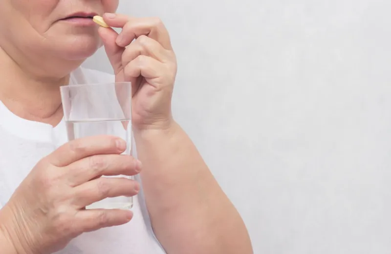woman drinking potassium iodide tablet and levothyroxine sodium, for the treatment of the thyroid gland, close-up, copy space, hormone, oncology, hypothyroidism