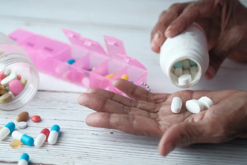 elderly woman pouring pills from bottle on hand, closeup view
