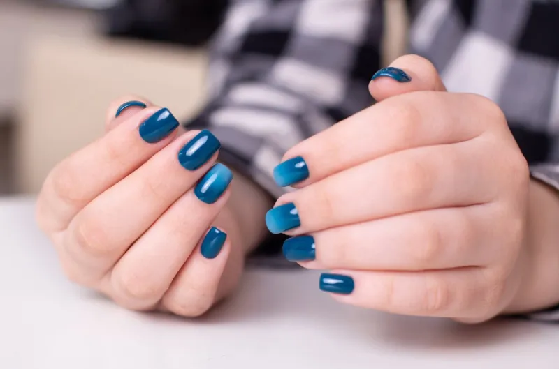 beautiful female hands with ombre manicure nails, blue gel polish