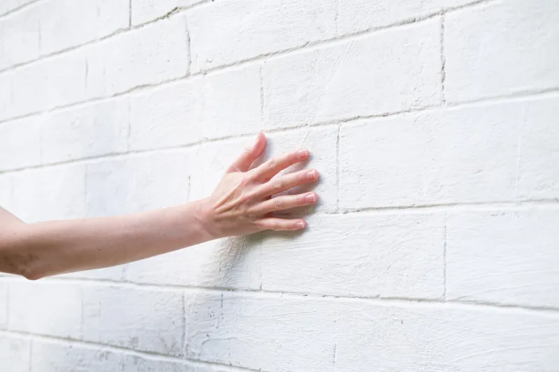 woman's hand on the background of a white brick wall a woman touches the old wall of the monastery