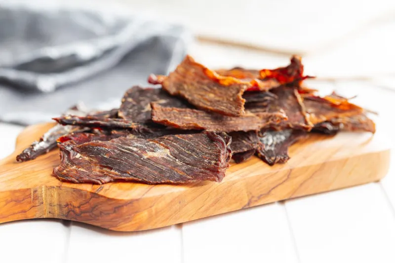 beef jerky meat dried sliced meat on a wooden cutting board