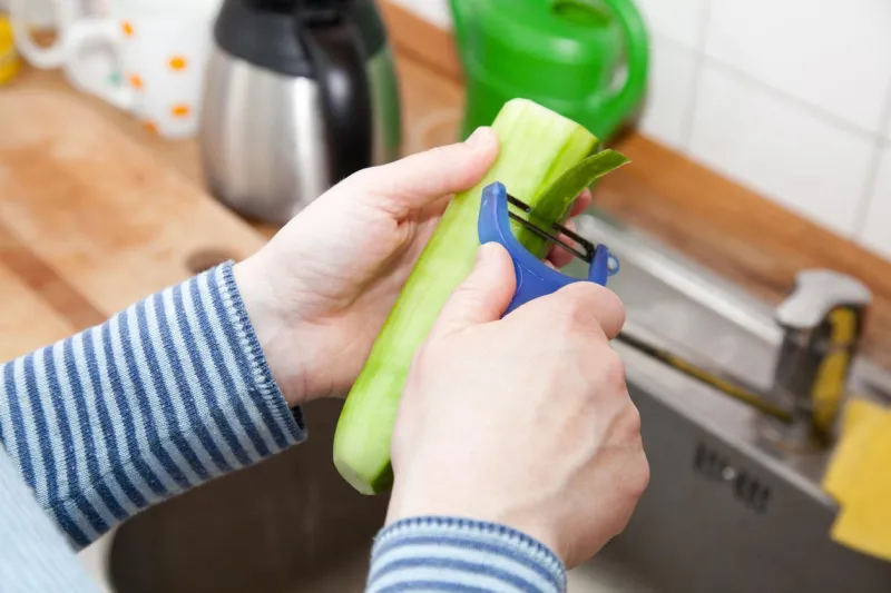 femme épluchant un concombre dans la cuisine