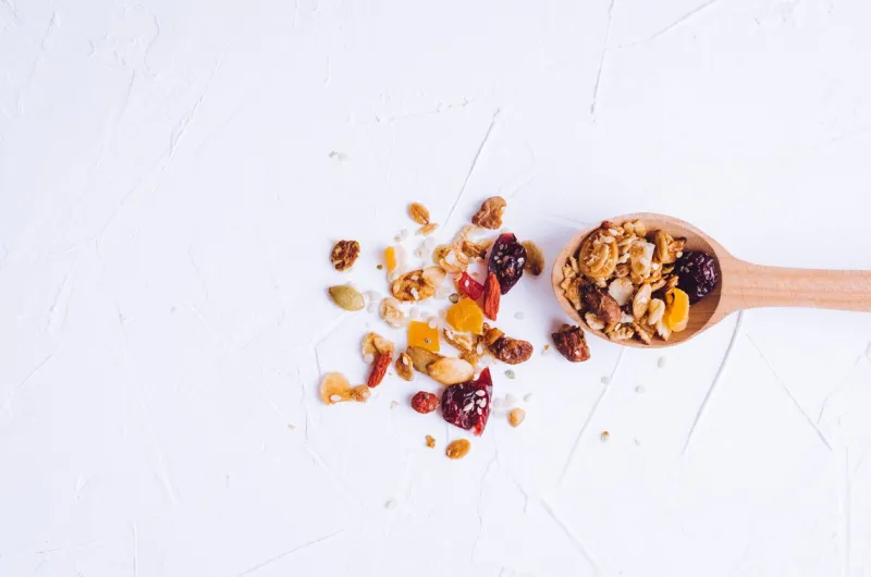 delicious homemade granola on wooden spoon on white background breakfast healthy food sweet dessert snack diet nutrition concept vegetarian food flat lay top view copy space
