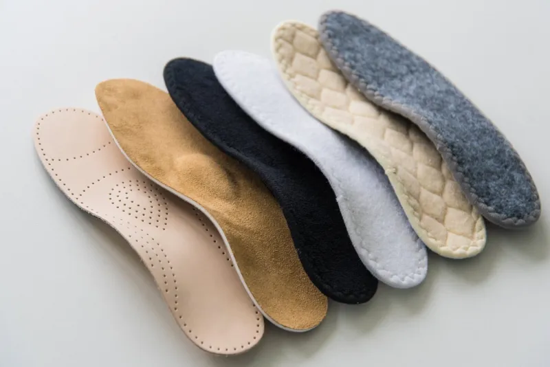 studio photo of orthopedic insoles a variety of orthopedic insoles are laid out in a row different colors and coatings  leather, cotton, microfiber