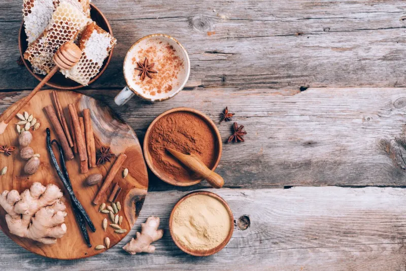 indian masala tea with spices tea with milk, cloves, ginger, cardamom, cinnamon, anise, vanile, honey, nutmeg on wooden background top view, copy space antiviral beverage healthy ayurvedic drink chai