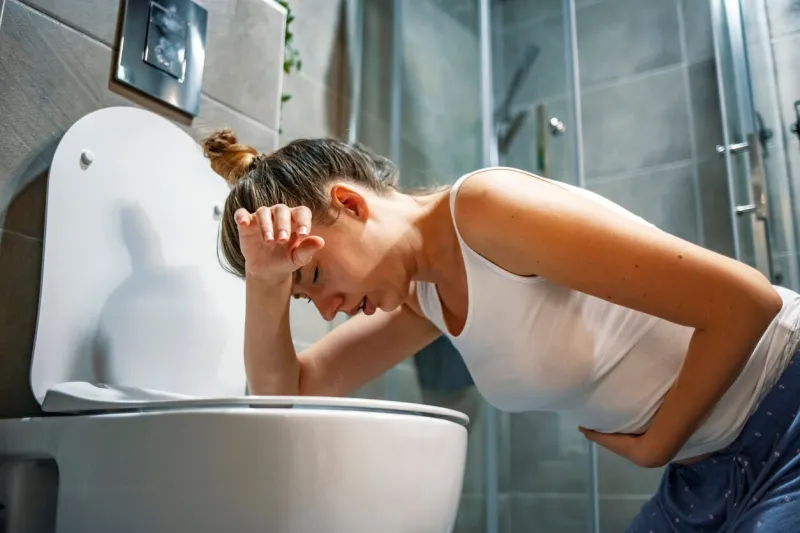 young caucasian woman in toilet - pregnant, drunk or illness concept young dark-haired woman vomiting in toilet woman getting sick and vomiting over a toilet bowl kneeling down with her arms resting on the seat