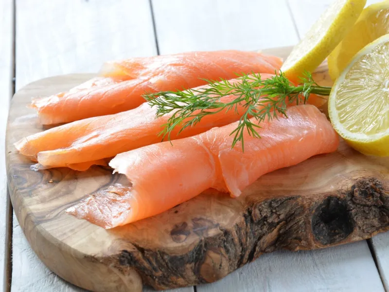 slices of smoked salmon and fresh lemon on wooden board