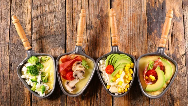 cheese raclette tray with vegetable and salami assortment- top view