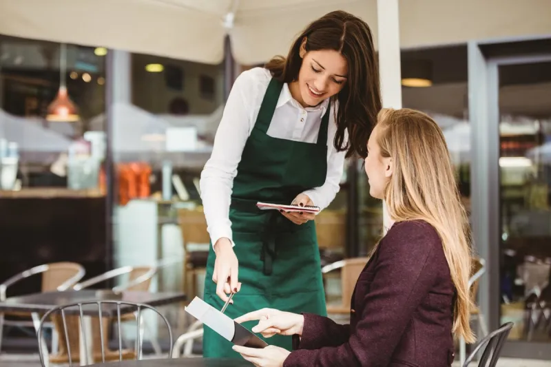 smiling waitress taking an order in cafe