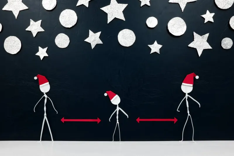 stick men figure wearing santa hat with red distance marker in between and silver stars and balls ornament background social distancing during christmas concept
