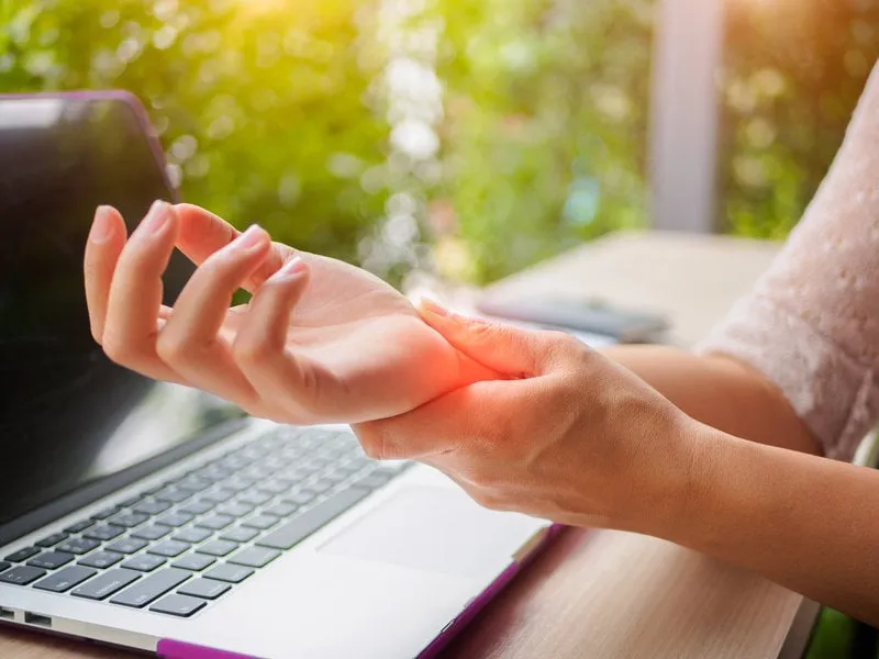 closeup woman holding her painful hand from using computer office syndrome hand pain by occupational disease