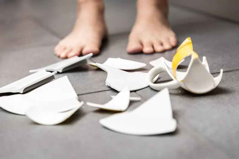 picture of a child making a dish and a glass of water broken on the kitchen floor the concept is dangerous for the body and young children inside the house