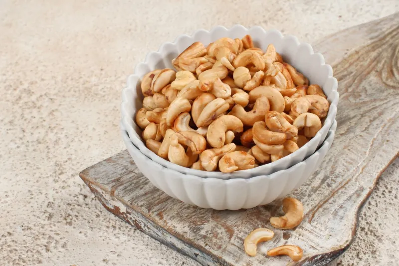 tasty cashew nuts in bowl on white table