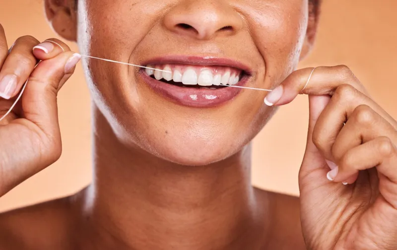 woman, hands and teeth with smile for dental floss, skincare or personal hygiene against a studio background closeup of female smiling and flossing in cosmetics for oral, mouth or gum care treatment