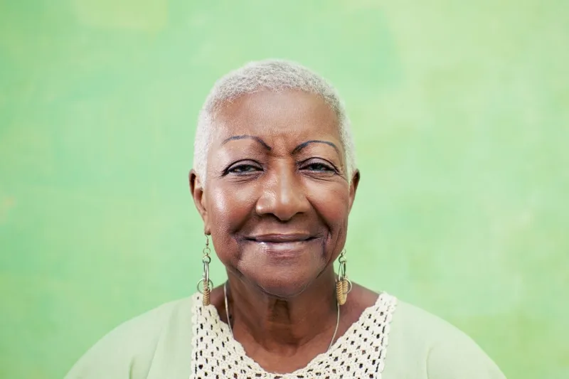 old black woman portrait, lady in elegant clothes smiling on green background copy space