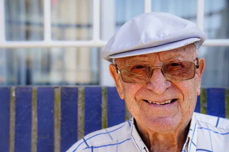 portrait of happy senior looking at camera smiling mature man with hat and glasses
